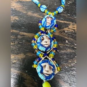 Handcrafted necklace with clay beads and three faces.